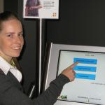Mevrouw Aendekerk, hoofd van de pati�ntenadministratie, toont hoe de pati�nt zich inschrijft via het touchscreen van Qmatic