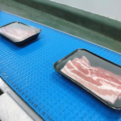 Varkensvlees in trays worden gewogen en geëtiketteerd